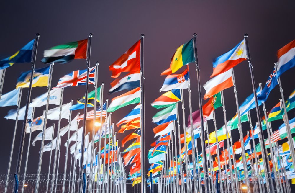 A variety of colorful flags fluttering in the breeze against a clear blue sky.